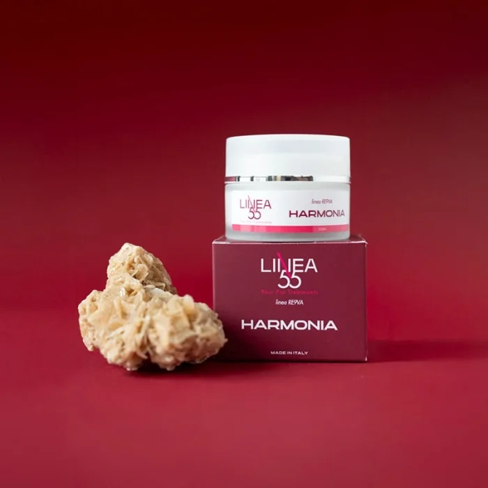 Vasetto di crema viso Harmonia Re9va di Linea55 con olio di Argan e burro di karité, con confezione e accessorio naturale su sfondo bordeaux.