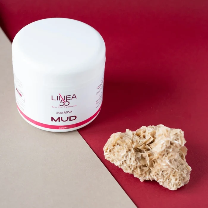 Barattolo bianco da 500ml di fango Mud Re9va di Linea55 con ingrediente naturale decorativo su sfondo bicolore beige e rosso.
