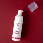 Flacone con dispenser da 150ml di mousse detergente Zen Scent Re9va di Linea55 con cappuccio trasparente aperto su sfondo rosso.